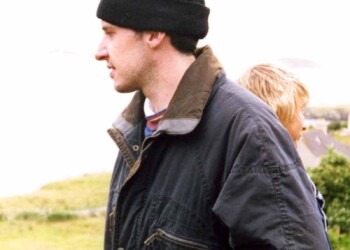 A man with a beanie hat on with a woman behind him