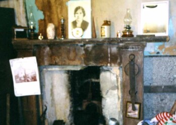 An old fireplace with lamps hanging above it.