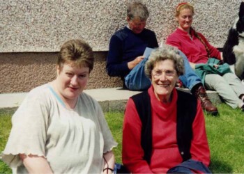 4 people and a dog sitting on the ground outside a building