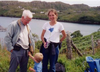 An older man, a younger woman and a child in front of a loch