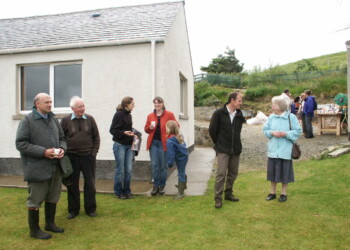 People talking and drinking tea outside a house