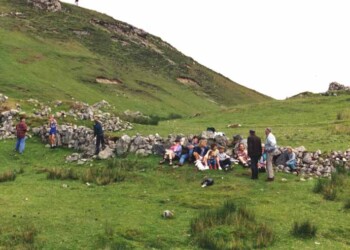 Relaxing in Stiomreway Group sitting and standing by dry stone wall