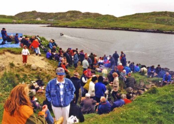 Relaxing on Eilean Chalum Cille in 1997 Group on grassy shoreline with boat motoring away
