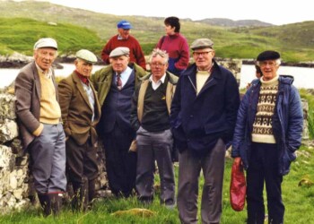 A group of members and friends on Eilean Chalum Cille in 1997 Group of mostly men standing in front of dry stone wall