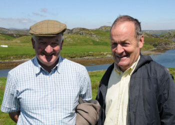2 men in the sunshine with a view over loch behind them