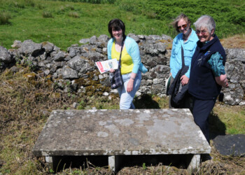 3 people looking at a raised horizontal stone slab